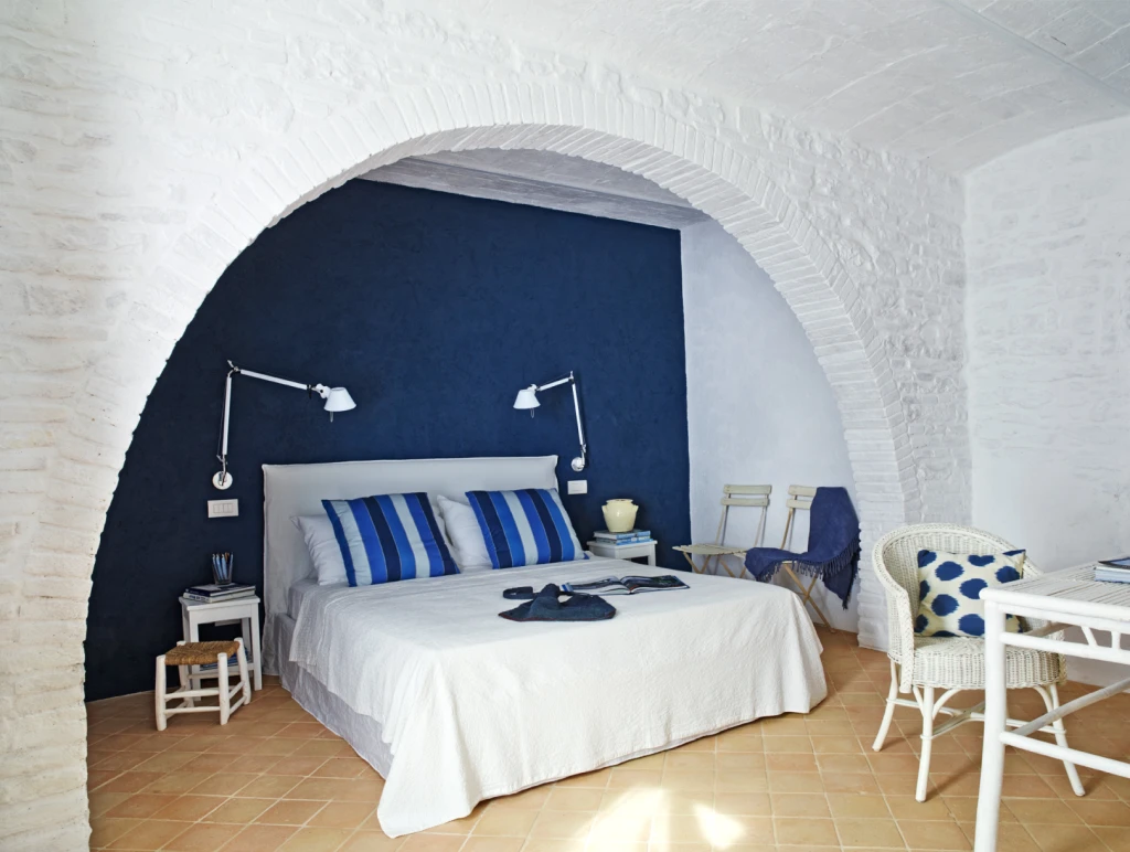 The Blue room: is on the ground floor and has its own private entrance. Cool white walls under ancient vaults, old terracotta floors, rich fabrics, a king-size bed by Gervasoni, and ocean-blue accents. The en-suite bathroom offers twin rain showers and an antique marble washbasin.